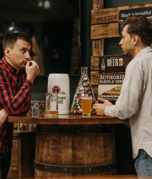 2 men in a bar talking over drinks to illustrate the setting of The Highway Pub