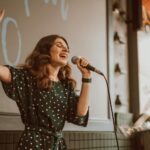 woman signing on stage with a mic as part of the live music renaissance