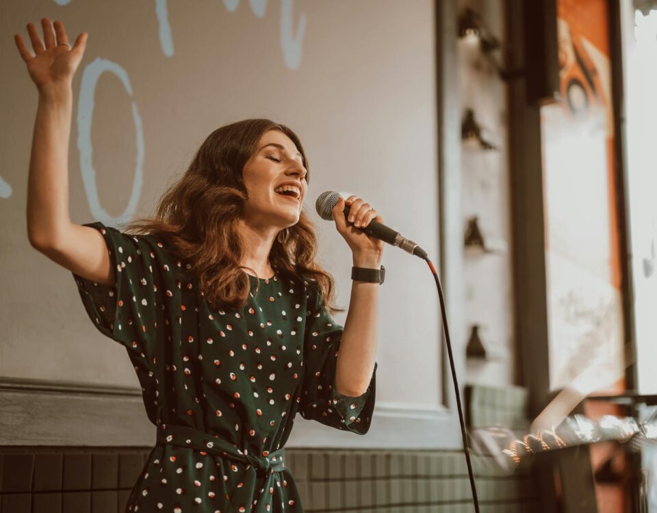 woman signing on stage with a mic as part of the live music renaissance