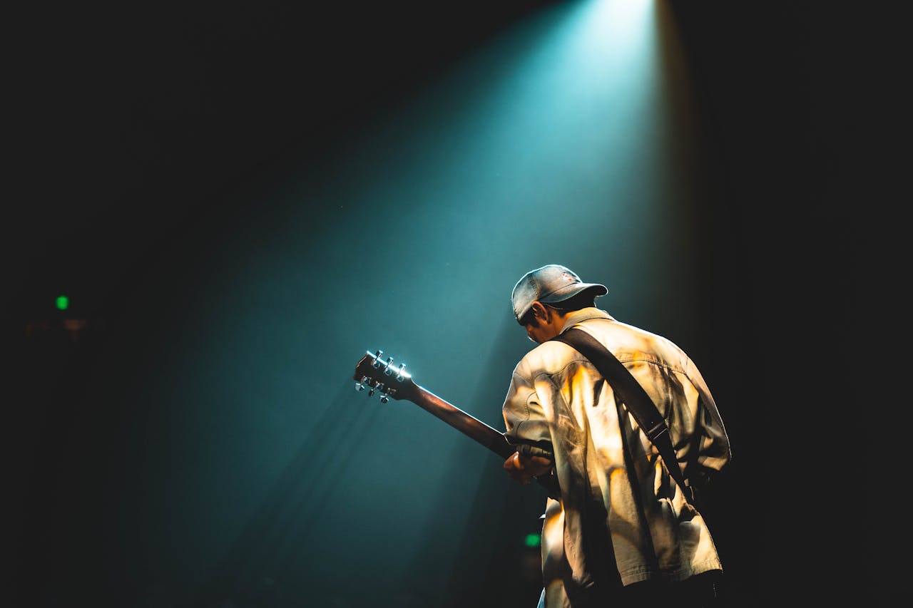 man standing under spotlight with a guitar as part of the live music renaissance