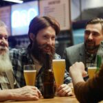 raise a glass with a group of men at a bar holding beer glasses