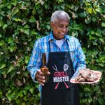 An Elderly man Holding a Plate of Grilled Meat and a Bottle of Beer to illustrate Celebrating Heritage Day
