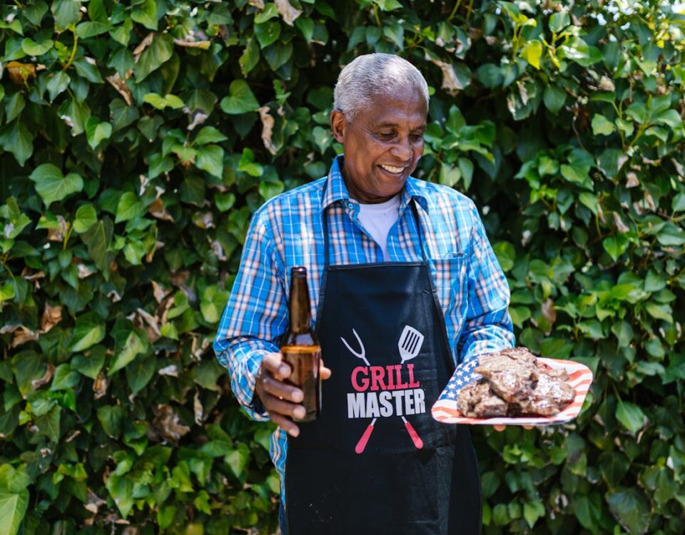 An Elderly man Holding a Plate of Grilled Meat and a Bottle of Beer to illustrate Celebrating Heritage Day