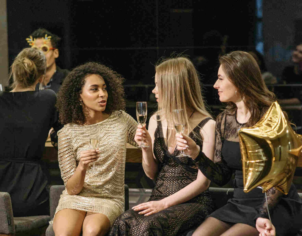 Women sitting on bar stools holding champagne as part of illustrating Event Essentials