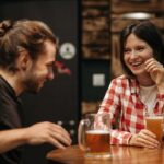 man using bar conversation starters to make a woman laugh at a bar counter