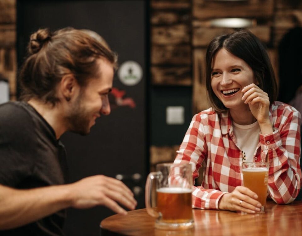 man using bar conversation starters to make a woman laugh at a bar counter