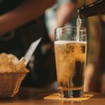 beer being poured inside glass from a bottle as part of illustrating the Draught Beer vs Bottled Beer debate