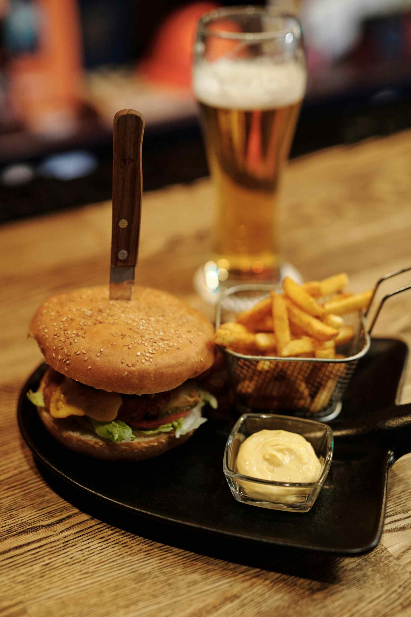 Burger and fries served with a cold lager beer on a wooden pub table
