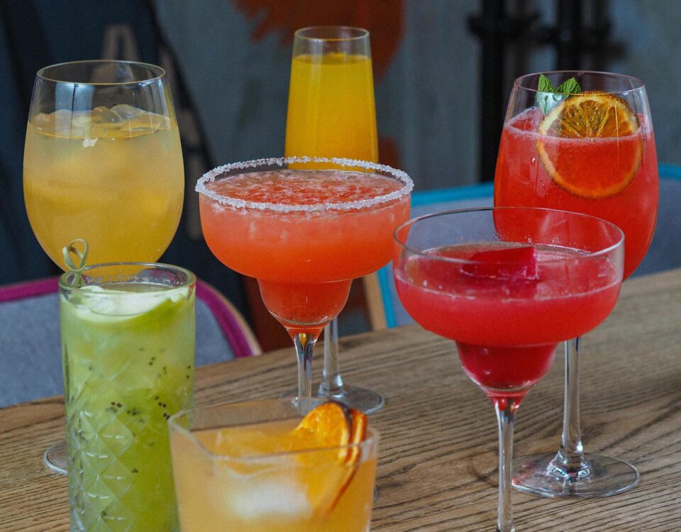 Assorted pub drinks including beer, cocktails, and spirits served on a wooden bar table