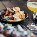 Close-up of pub food platter with wings, chips, and drinks ready for pairing