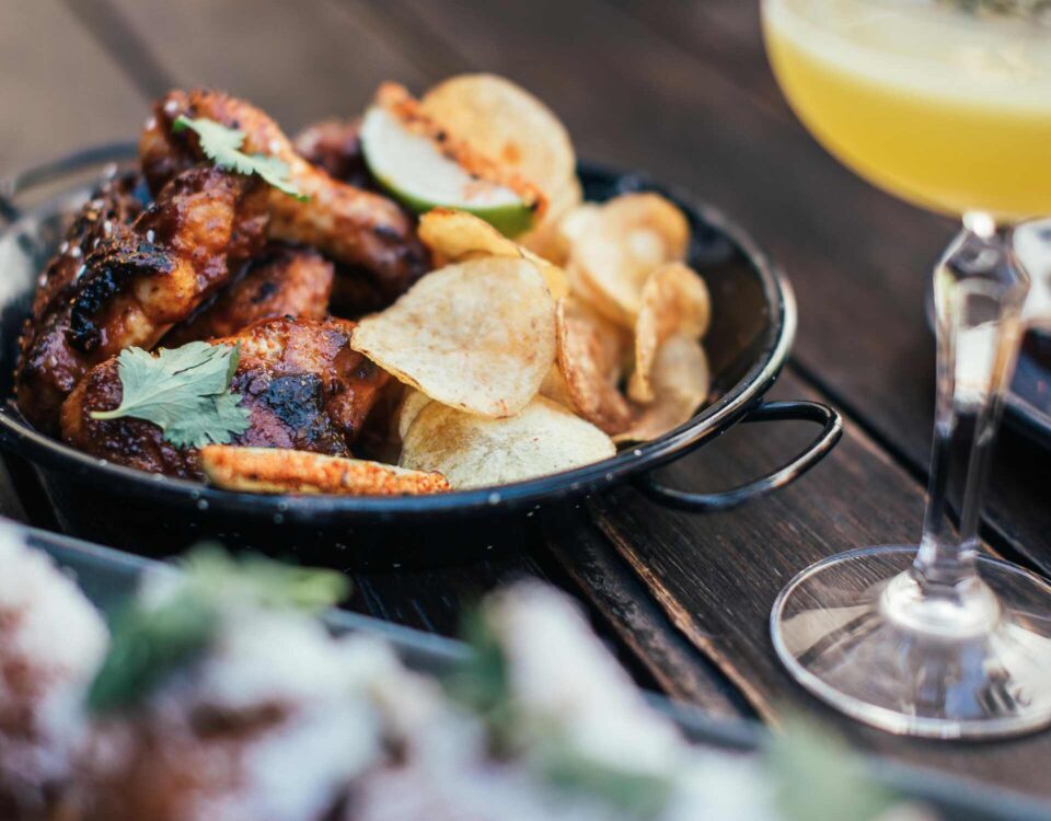 Close-up of pub food platter with wings, chips, and drinks ready for pairing