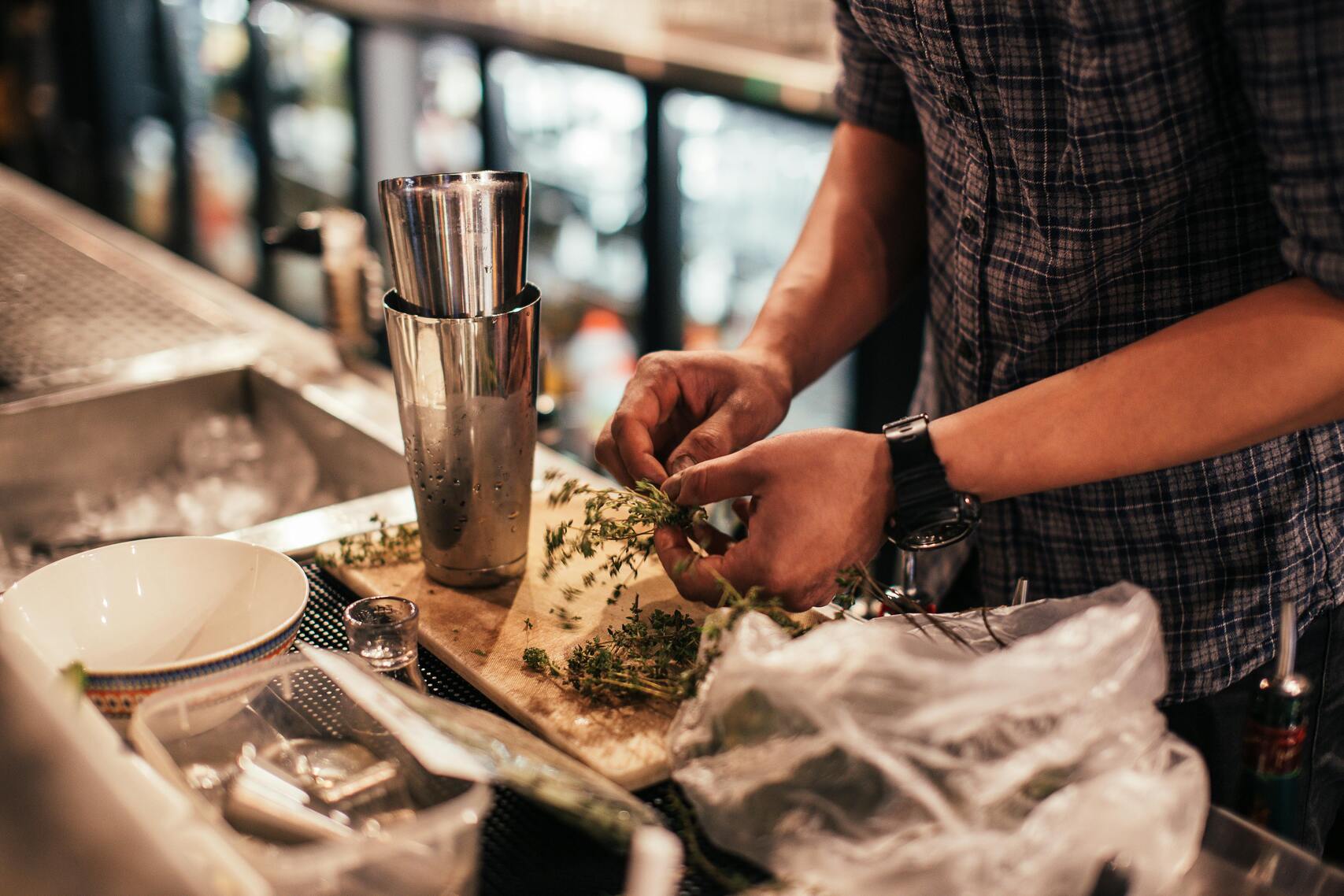 Bar staff preparing cocktails with fresh ingredients behind a pub counter