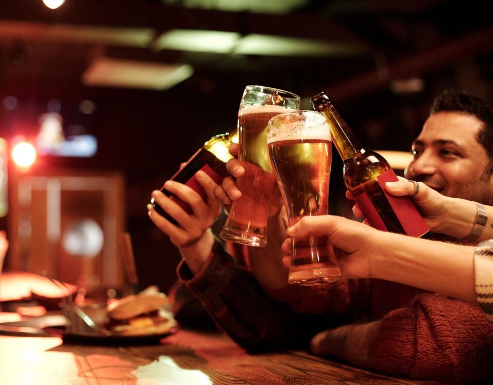 Friends enjoying match-day food pairings with drinks while watching rugby at a local pub.
