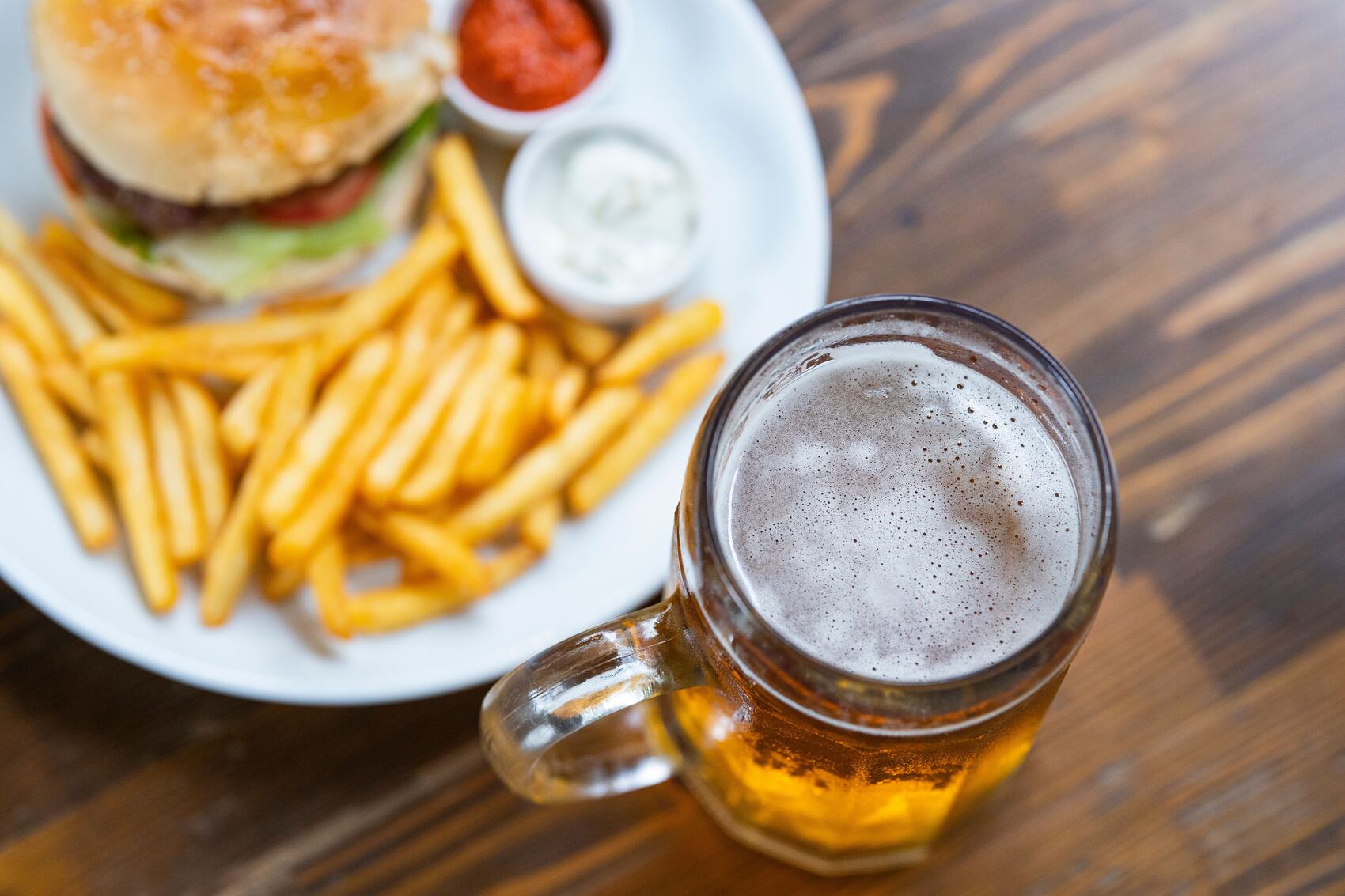 Match-day food pairings including burgers, wings, and beers on a pub table before a rugby game.