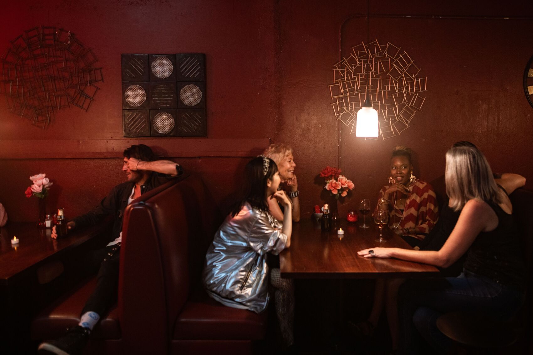 People seated in a corner booth enjoying food, drinks, and conversation in a welcoming pub setting